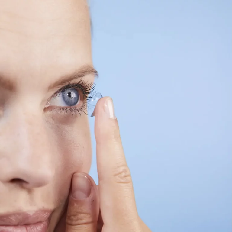 Frau mit blauen Augen setzt eine Kontaktlinse ein.